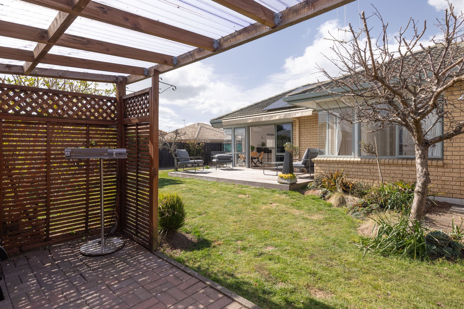 A Papamoa Beach home with sunny outdoor living under a pergola